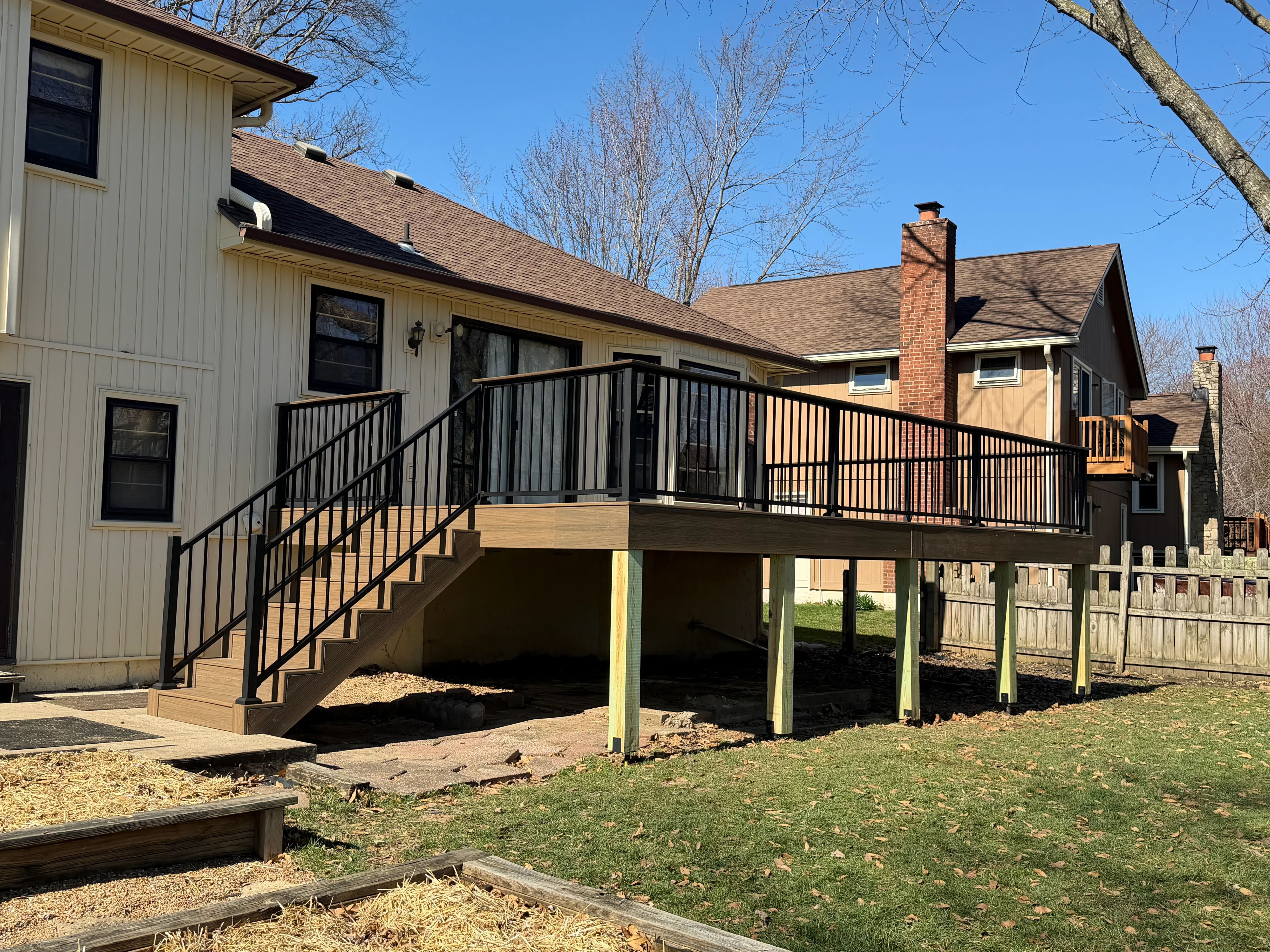 Elevated composite deck with black metal railings and stairs attached to residential home