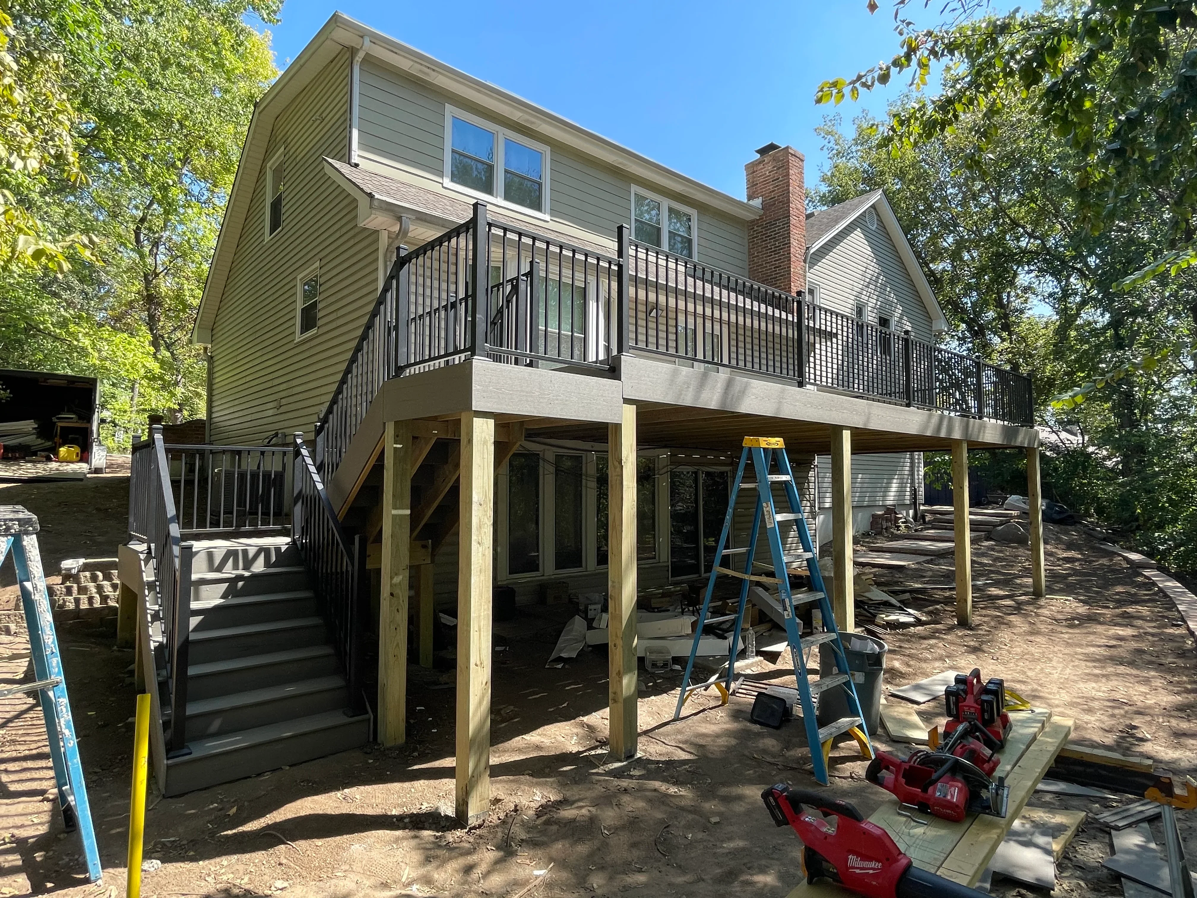 Elevated composite deck with black railings, pressure-treated posts, and under-deck covered structure during construction