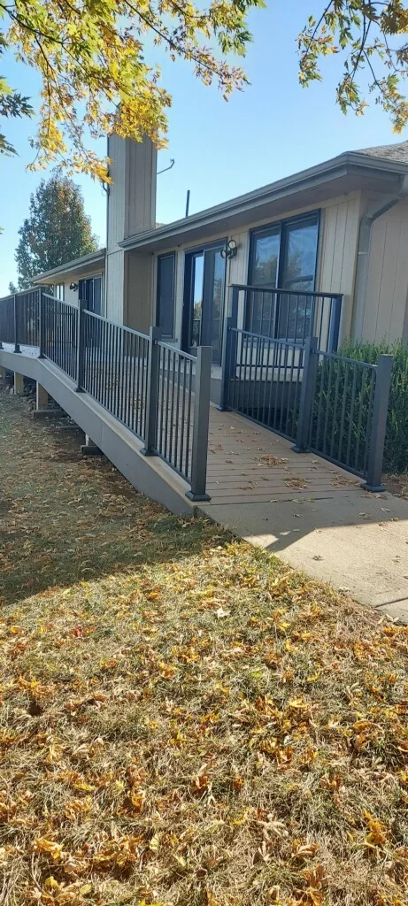 Elevated composite deck with black metal railing and spindles attached to residential home