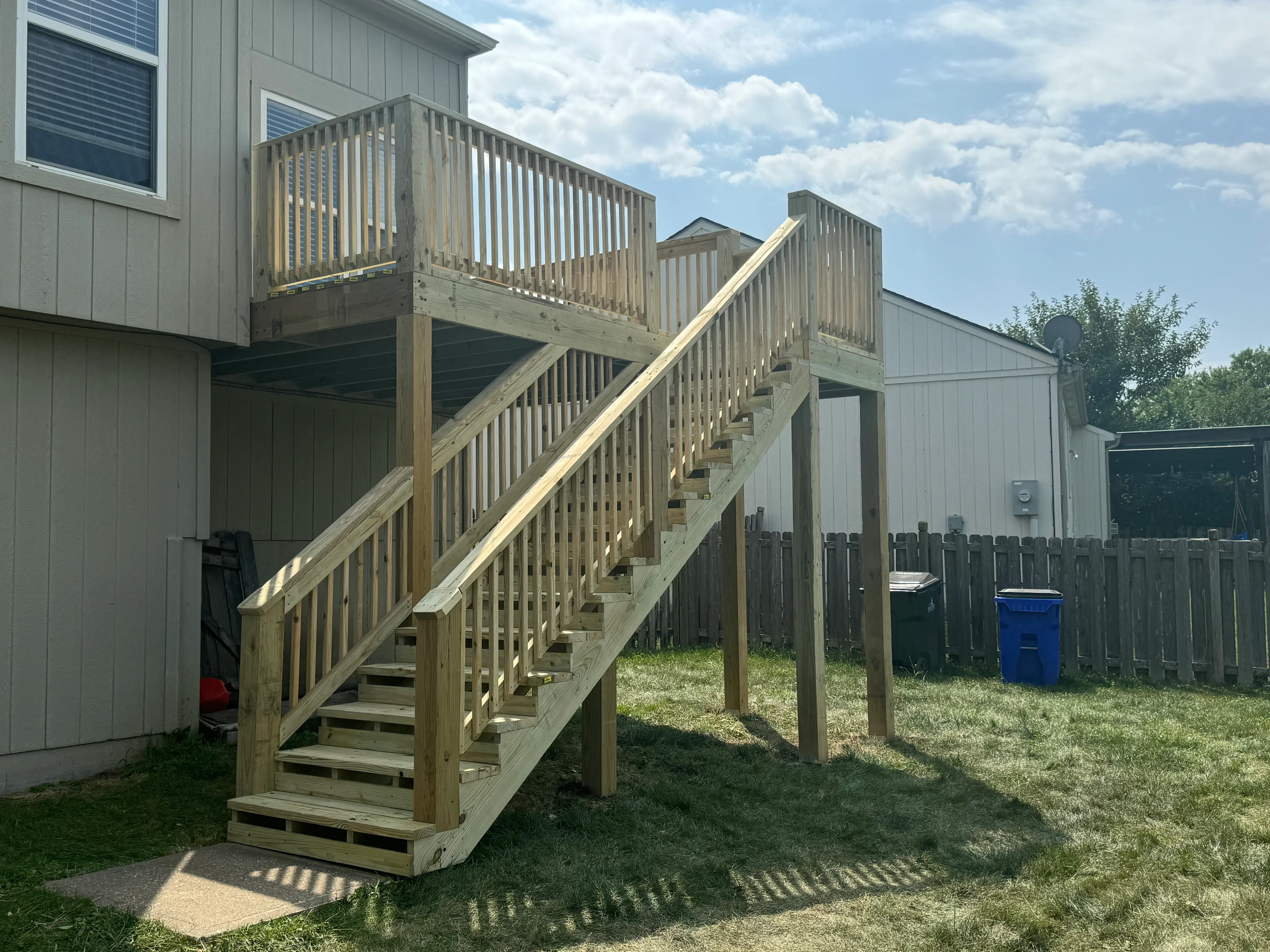 Elevated pressure-treated wood deck with stairs, landing, and vertical spindle railings