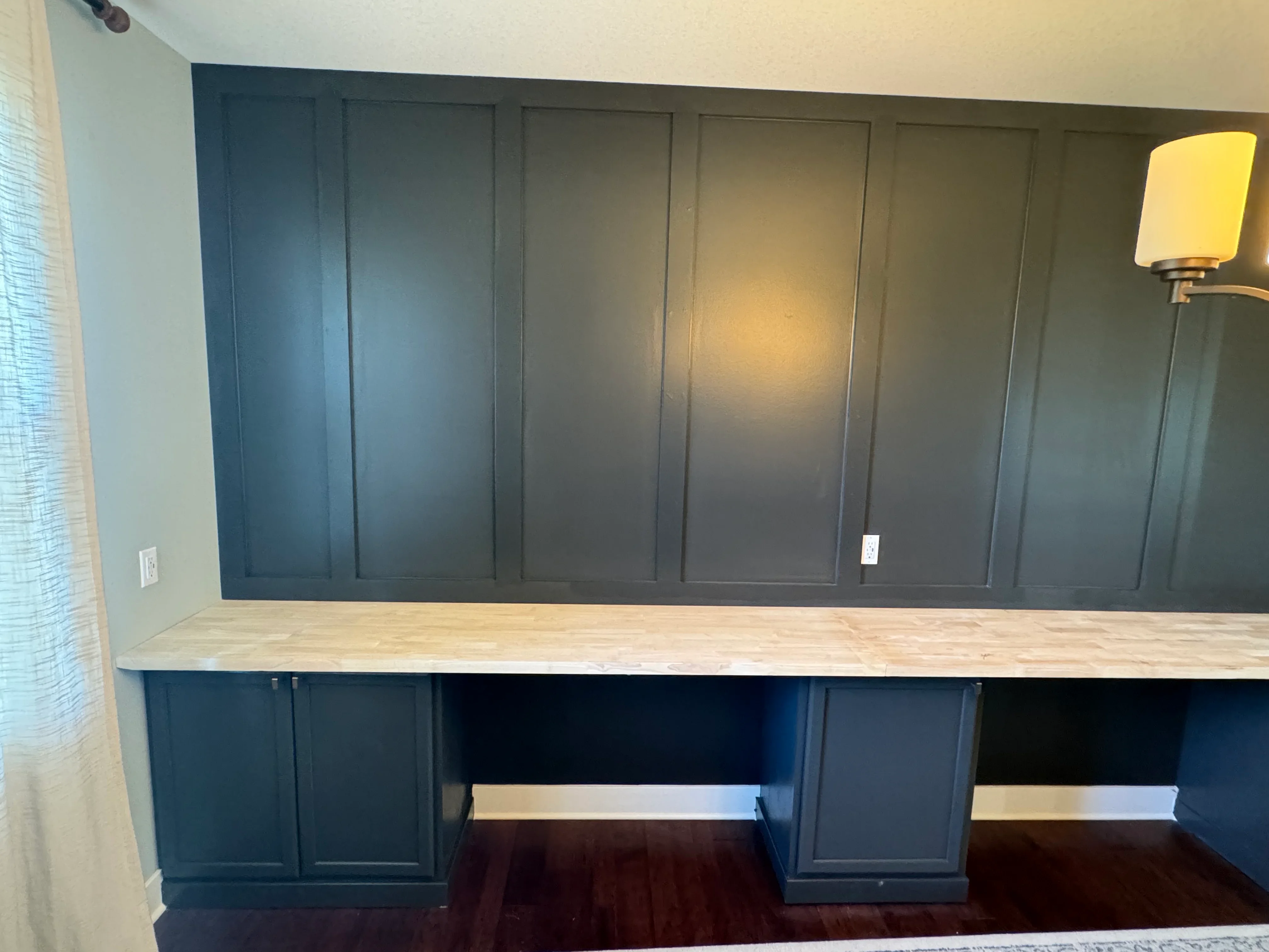 Dark blue painted built-in cabinetry with light wood countertop and recessed panel doors