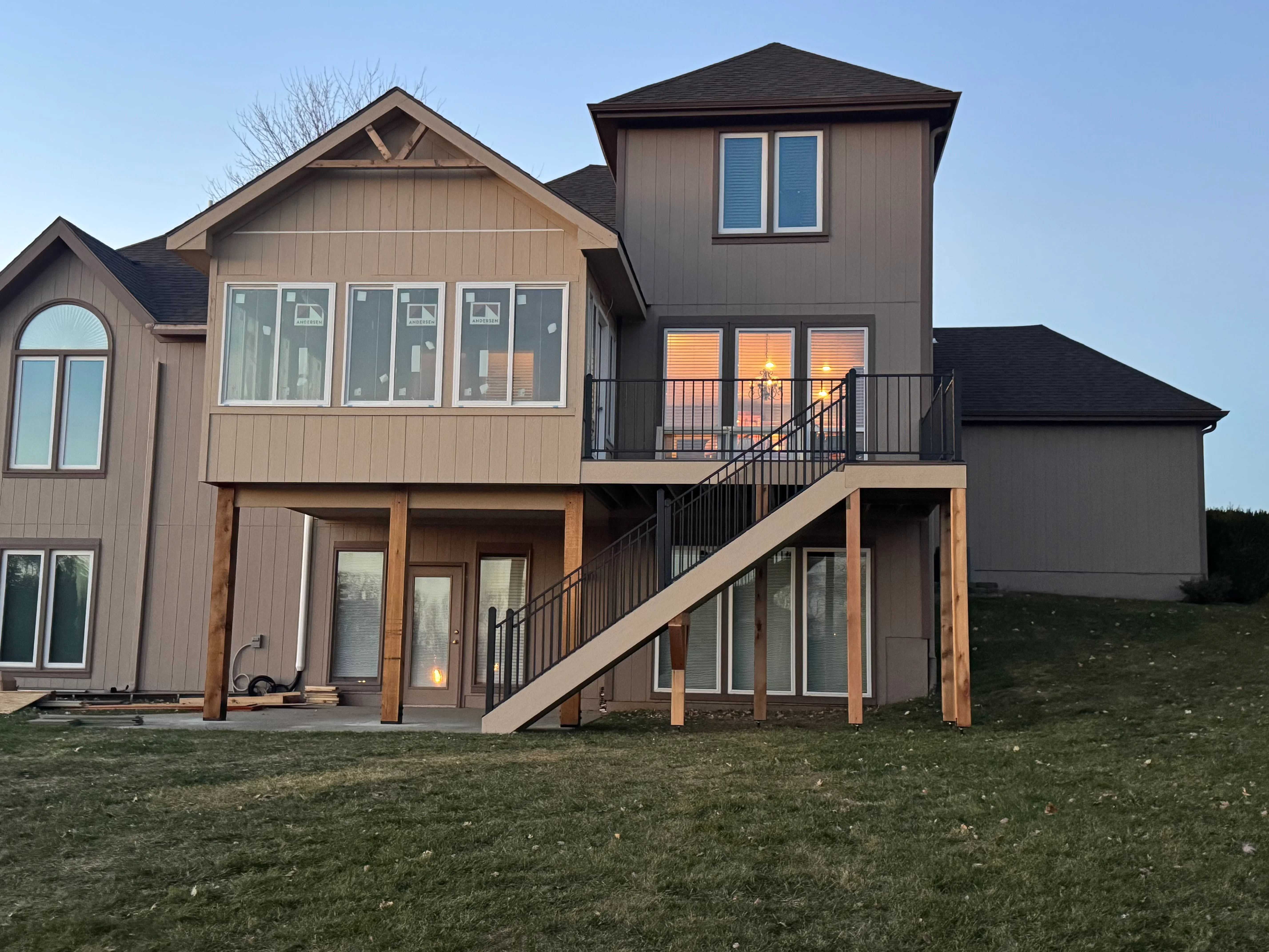 Two-tier composite deck with black railings, wood posts, and stairs on residential home