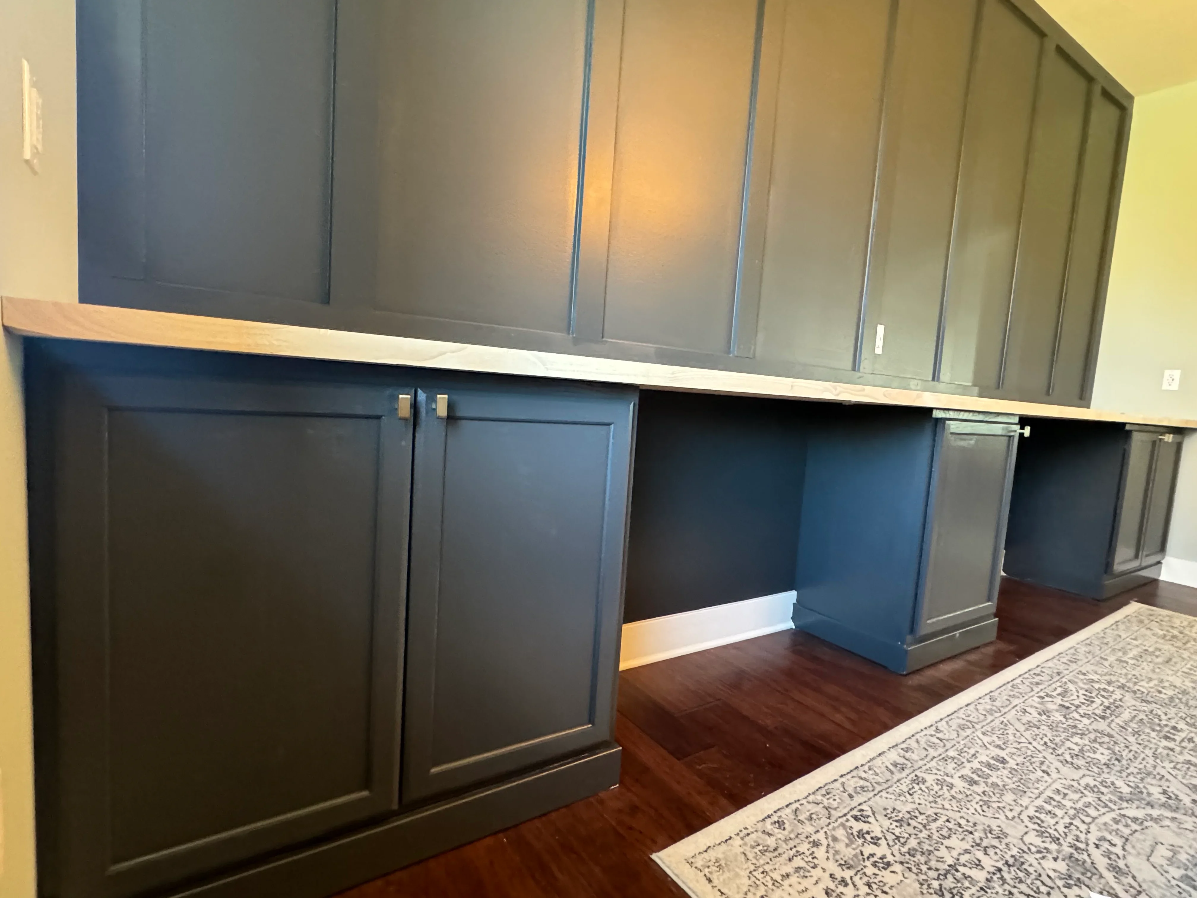 Two-tone painted built-in cabinetry with shaker doors, brass hardware, and wood countertop